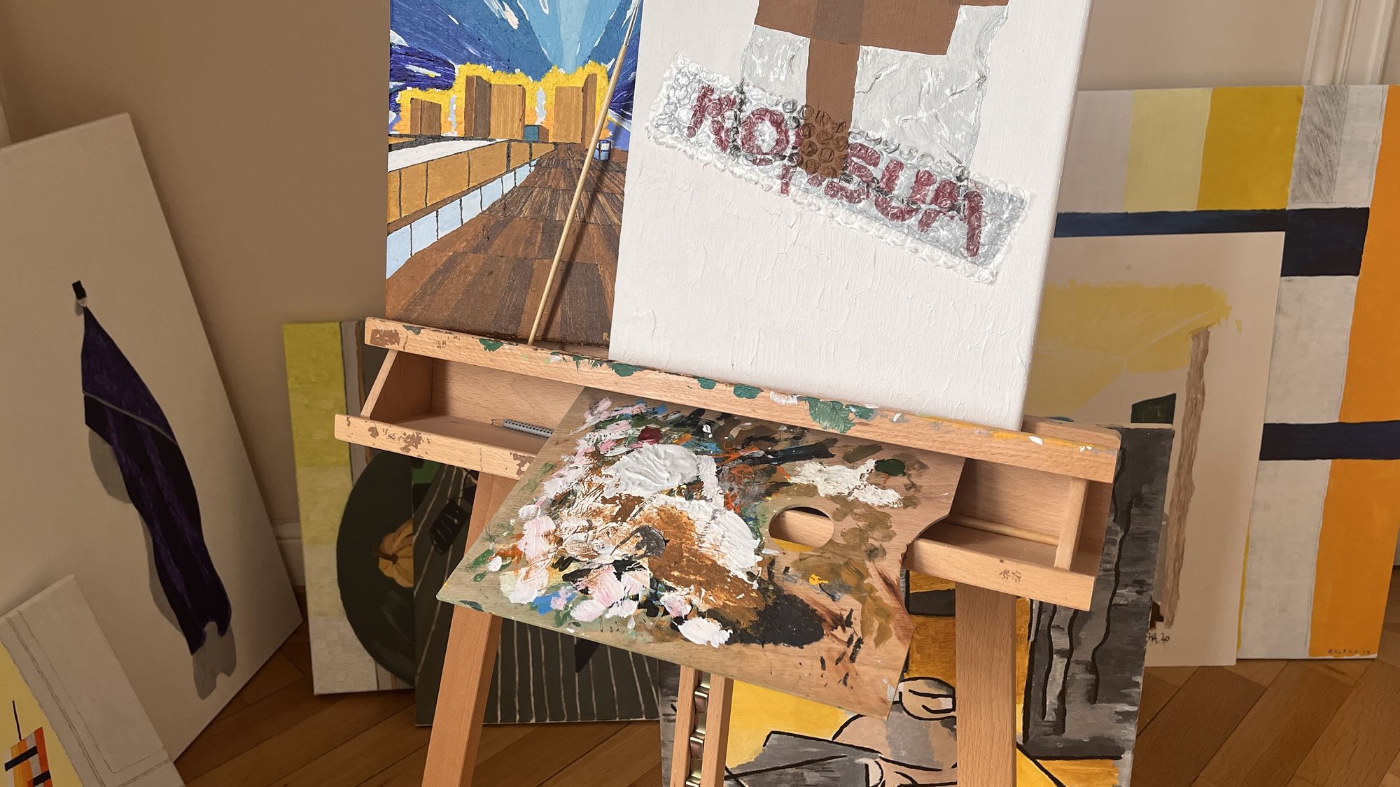 Staffelei im Atelier, umgeben von angelehnten Leinwänden
